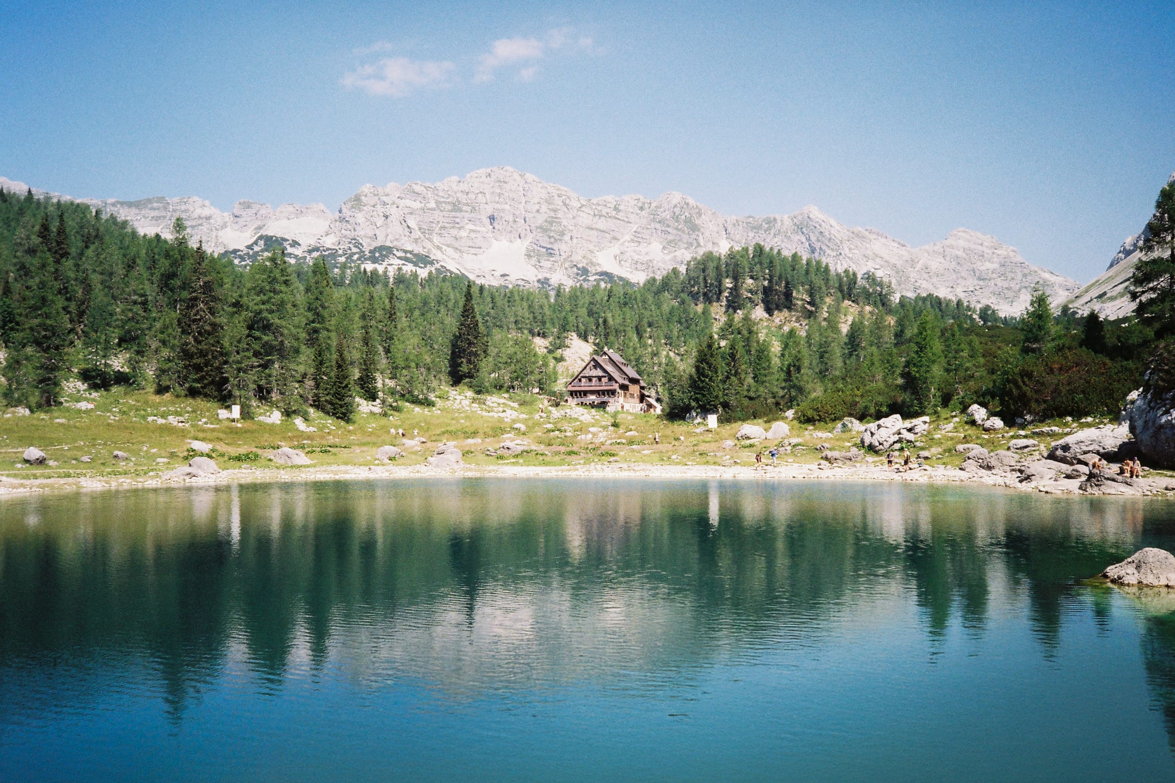 An alpine lake below limestone peaks, with a mountain hut on the far shore